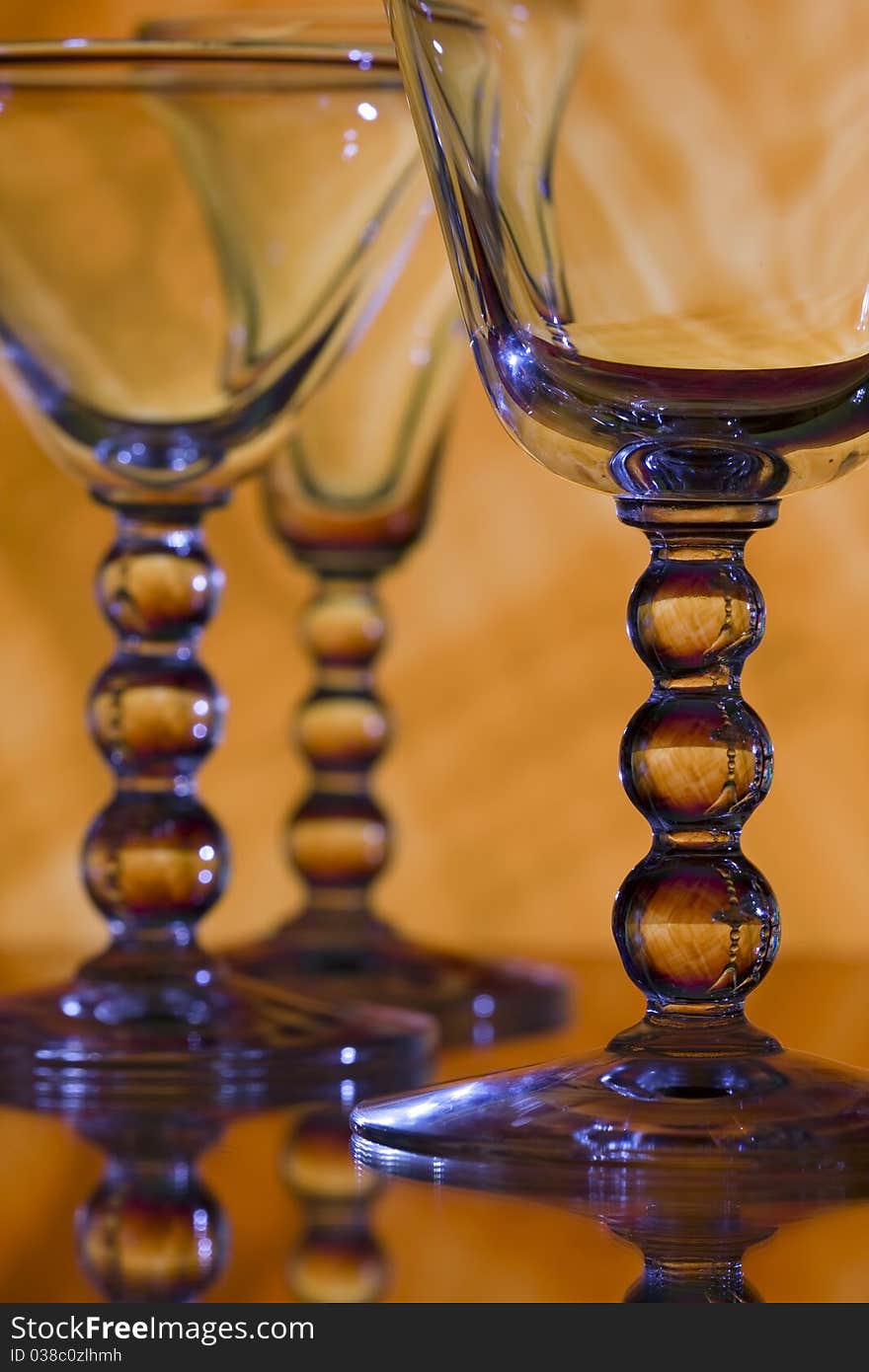 Macro of wine glasses with round shaped stems on orange background. Macro of wine glasses with round shaped stems on orange background