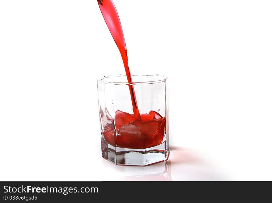 Red cocktail being poured into a glass on white background