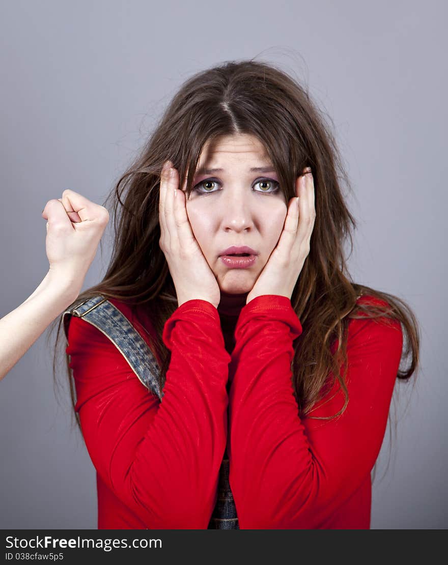 Sad girl in red and hand fist. Studio shot.