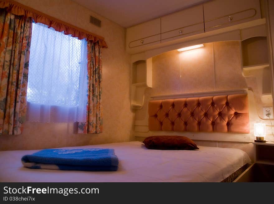 A scene inside of a comfortable, romantic bedroom with nightstands and lamps in luxury mobile home or motor home. A scene inside of a comfortable, romantic bedroom with nightstands and lamps in luxury mobile home or motor home.