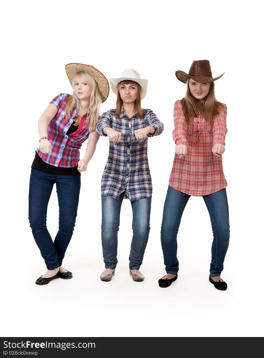 Three girls in hats imitate horse riding on a white background