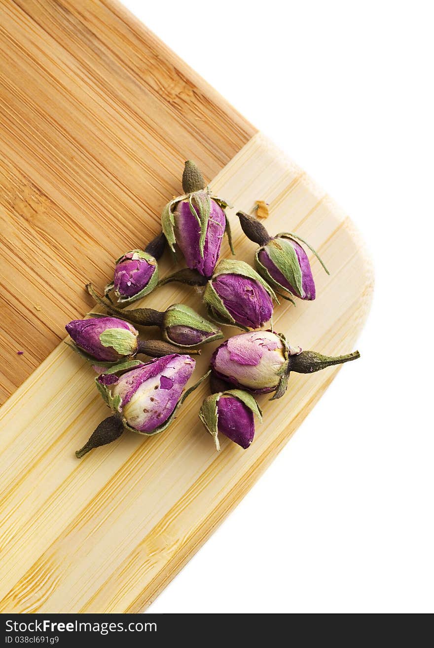 Dried tea roses on a bamboo cutting board