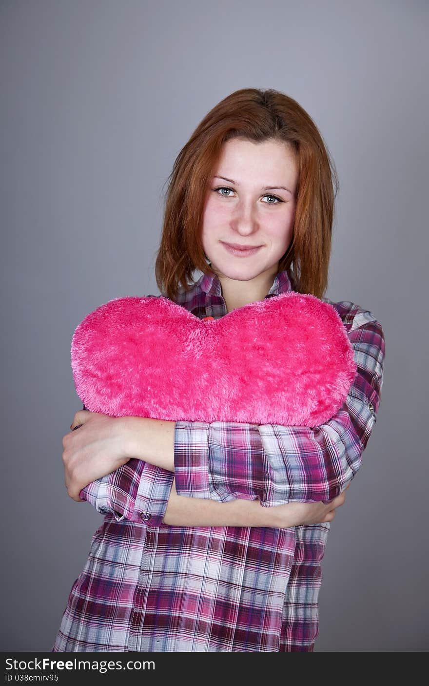 Red-haired girl with heart toy. Studio shot.