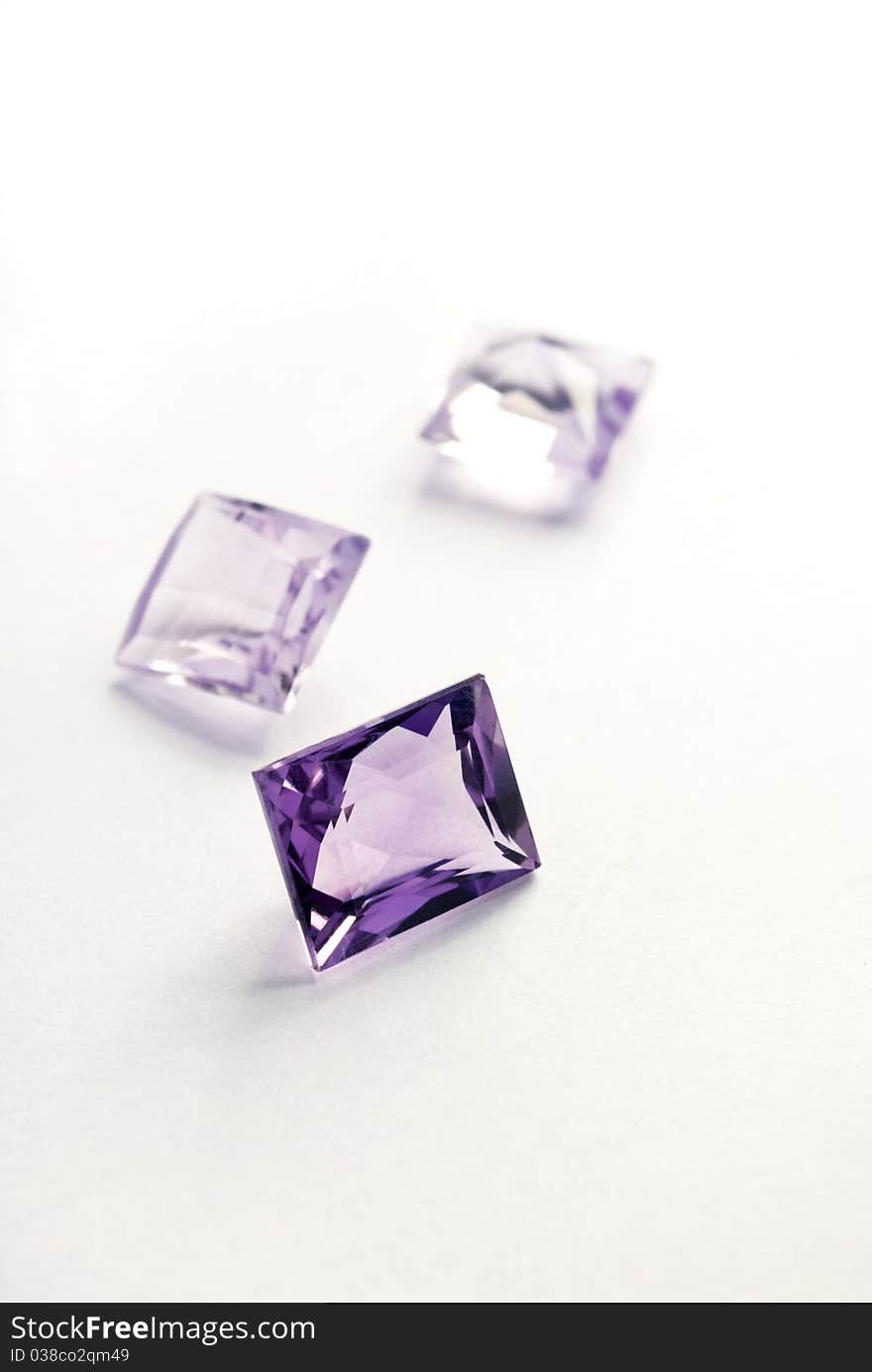 A close-up image of three princess-cut amethysts on a white back ground