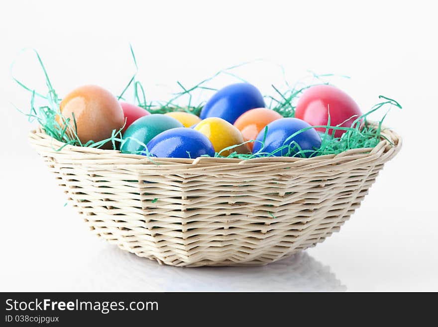 Colored easter eggs in a basket on white background