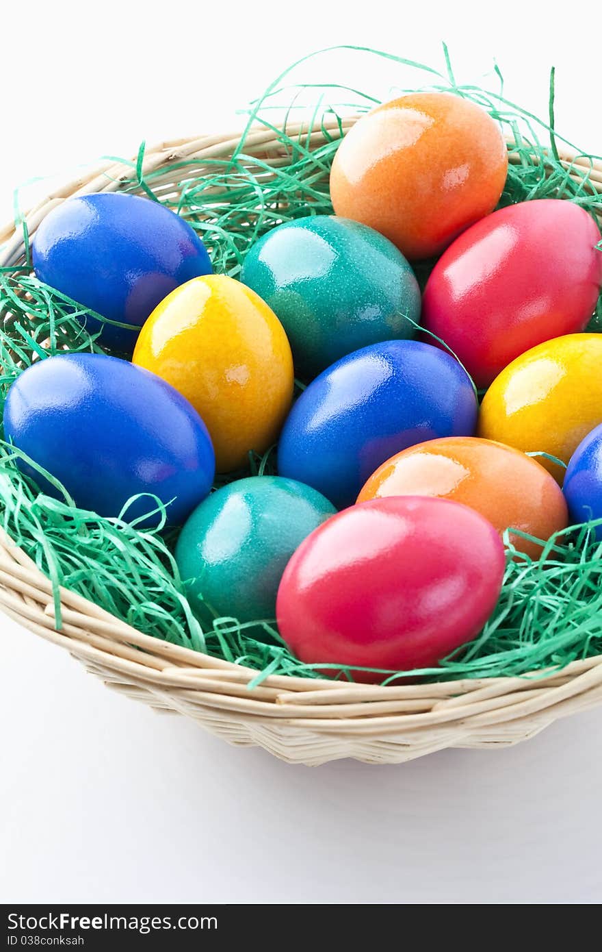 Colored easter eggs in a basket on white background