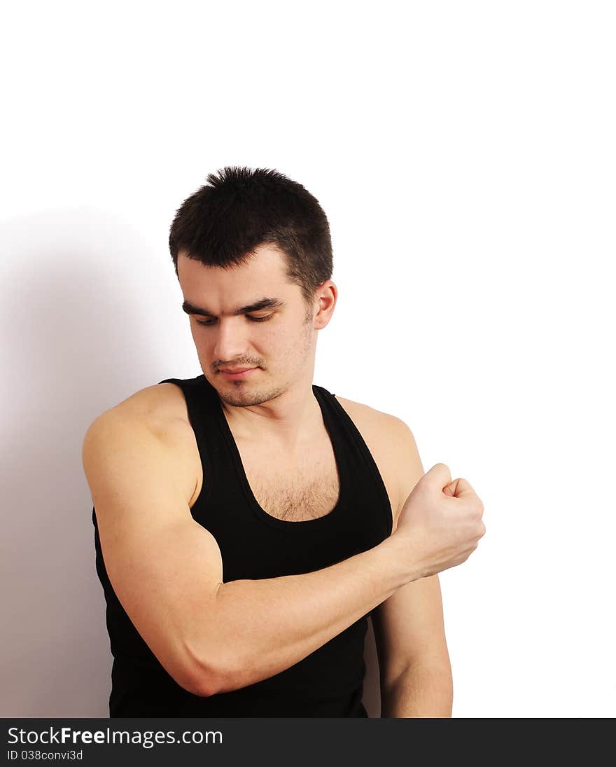 Portrait of a handsome young man slooking at his muscles. Portrait of a handsome young man slooking at his muscles