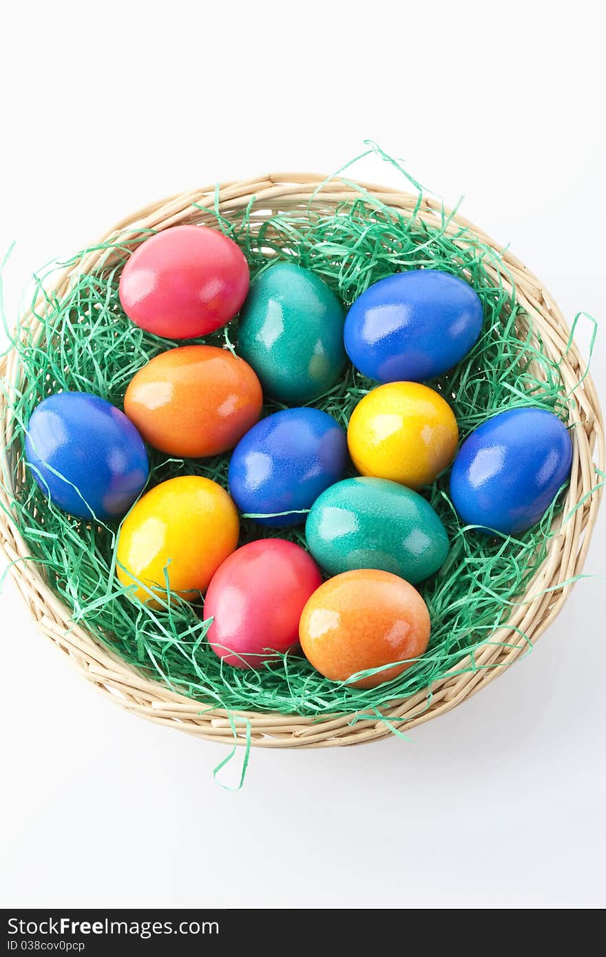 Colored easter eggs in a basket on white background