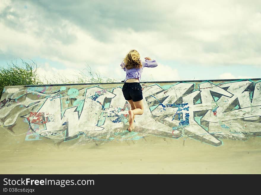 A little girl running up the ramp of a skate park. A little girl running up the ramp of a skate park.