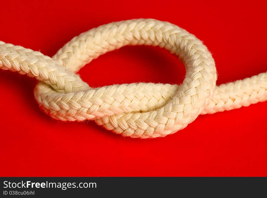 Knot of white rope on red background