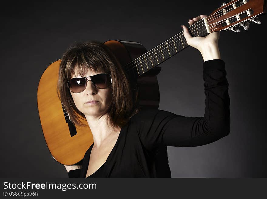 Woman posing with guitar on shoulders.