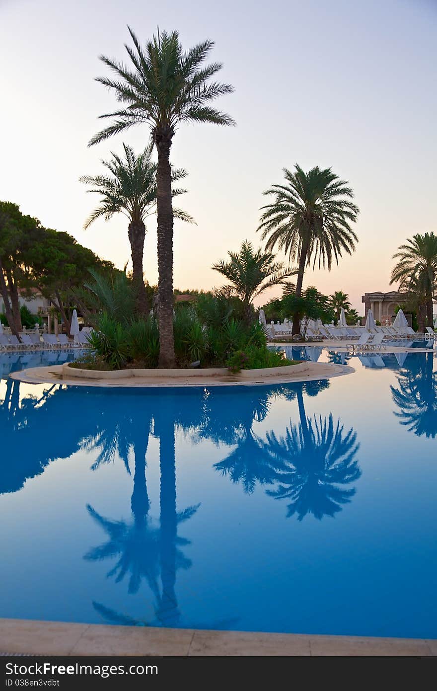 Sunrise on resort swimming pool with lounge chairs. Sunrise on resort swimming pool with lounge chairs