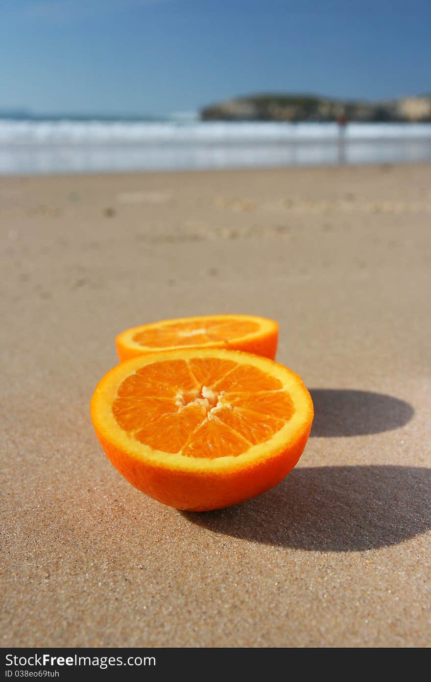 Cut orange on sand on beach