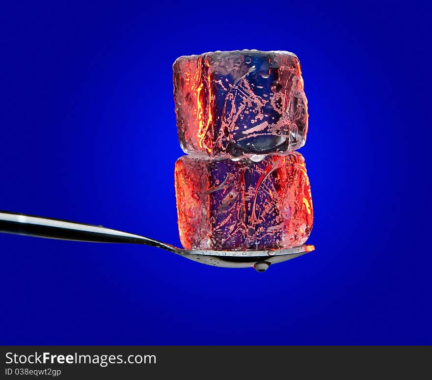 Ice cubes on spoon on blue background