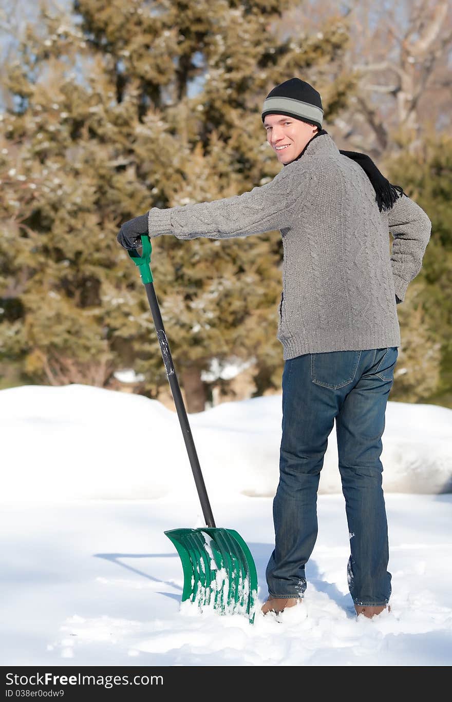 A man shoveling his driveway looking over his shoulder and smiling. A man shoveling his driveway looking over his shoulder and smiling