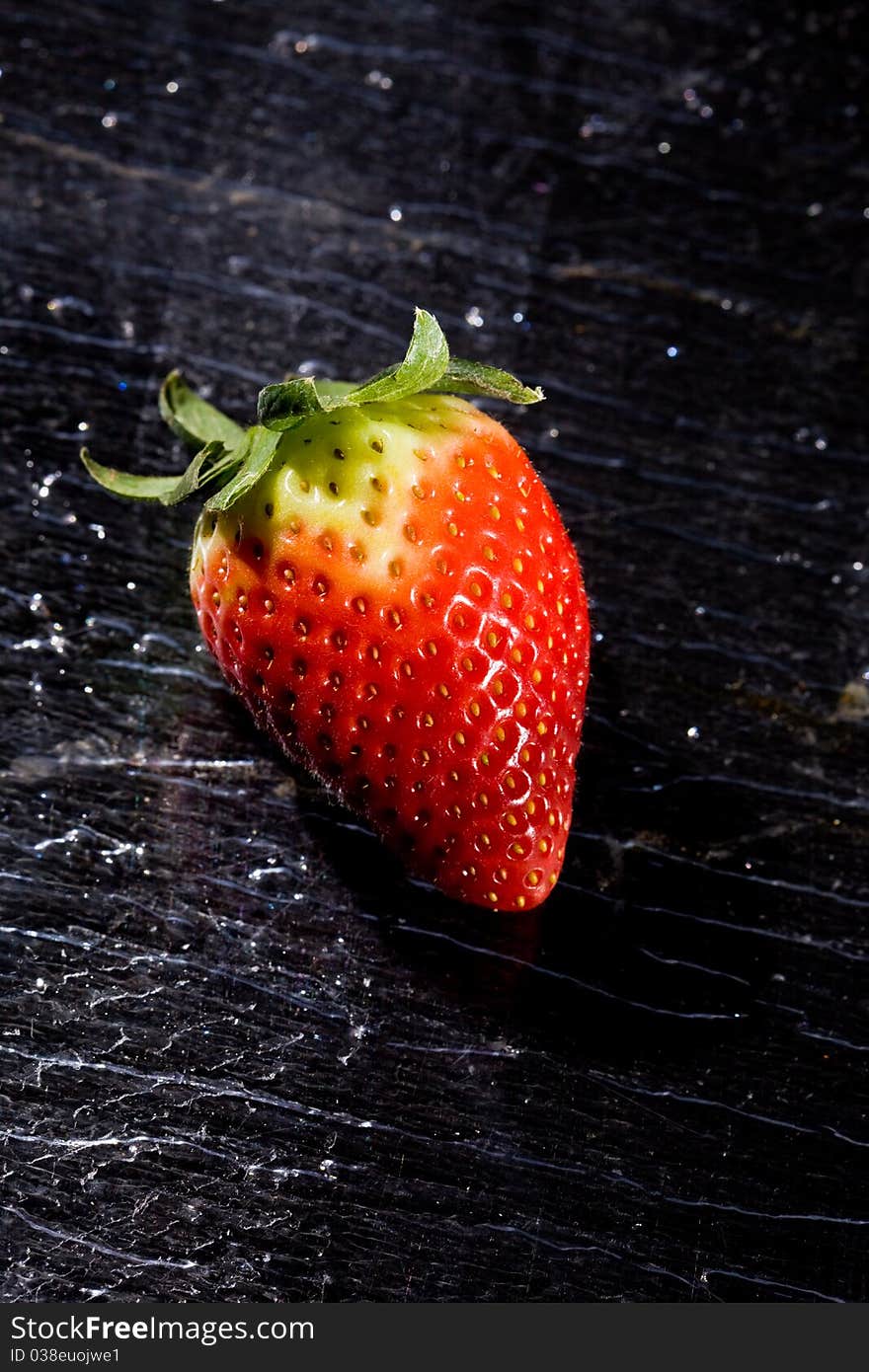 Photo of red strawberry on black glass table. Photo of red strawberry on black glass table