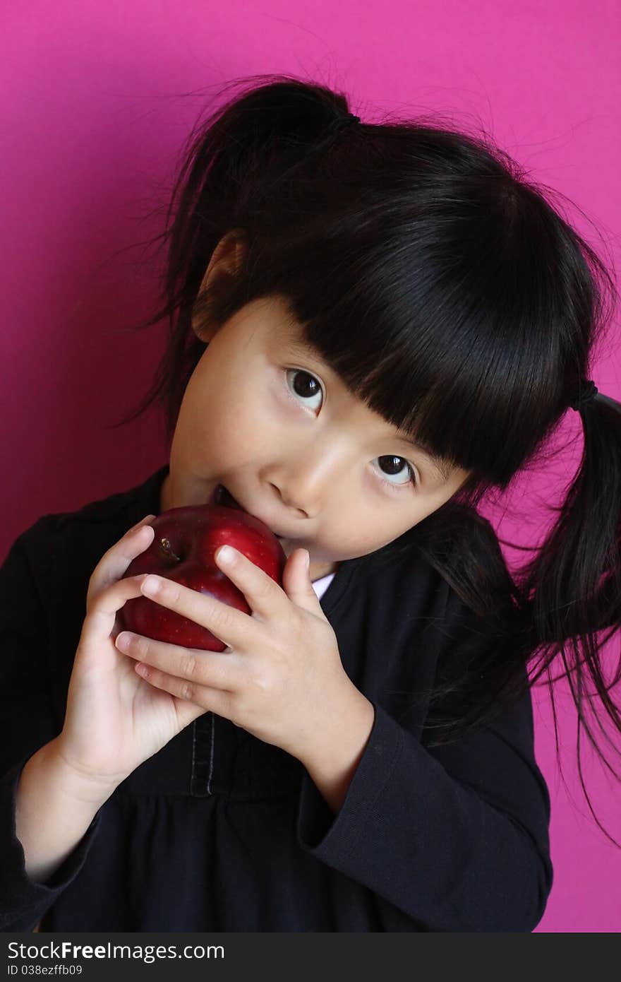 little asian chinese girl eating an apple. little asian chinese girl eating an apple