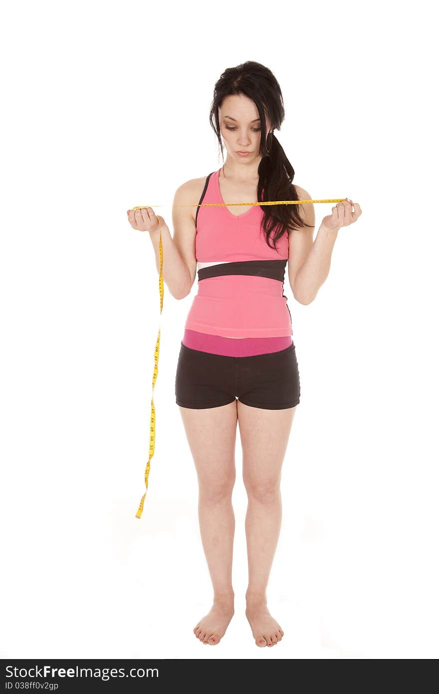 A woman is standing and holding a measuring tape dressed in shorts and a tank top. A woman is standing and holding a measuring tape dressed in shorts and a tank top.