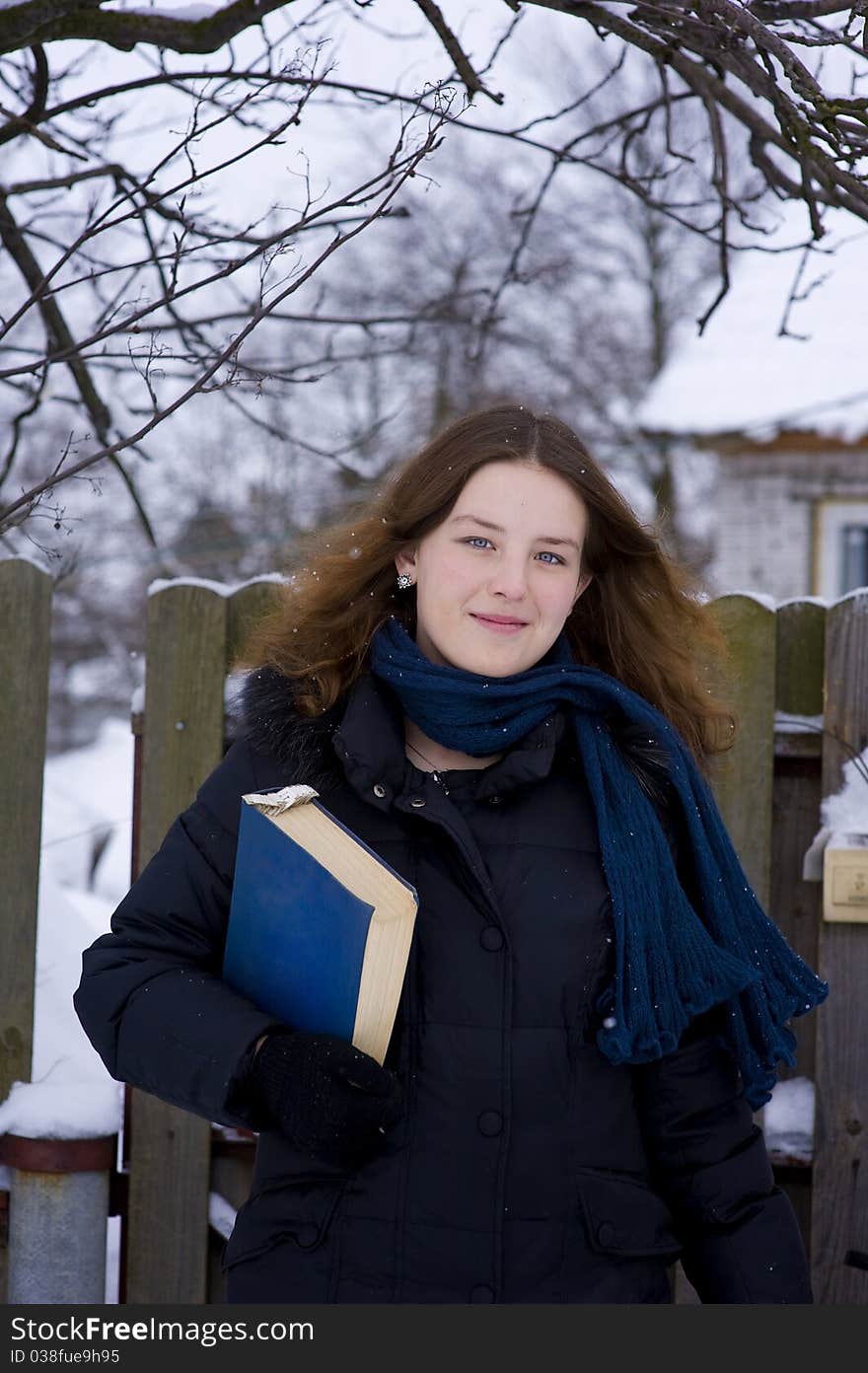 Smiling young girl with book in winter