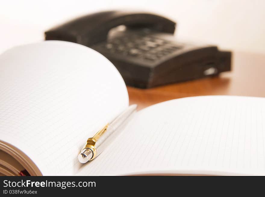 Open notepad  with pen and wired phone on a office desk. Open notepad  with pen and wired phone on a office desk