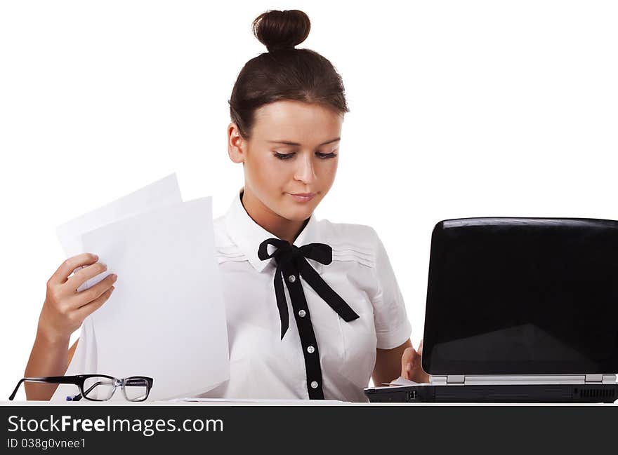 Young woman wearing glasses sitting behind a desk and a laptop computer goes through the documents. A series of modern, airy office. Young woman wearing glasses sitting behind a desk and a laptop computer goes through the documents. A series of modern, airy office.