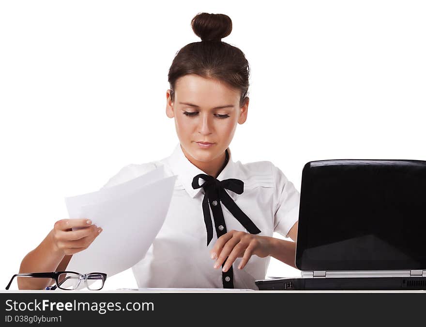 Young woman wearing glasses sitting behind a desk and a laptop computer goes through the documents. A series of modern, airy office. Young woman wearing glasses sitting behind a desk and a laptop computer goes through the documents. A series of modern, airy office.