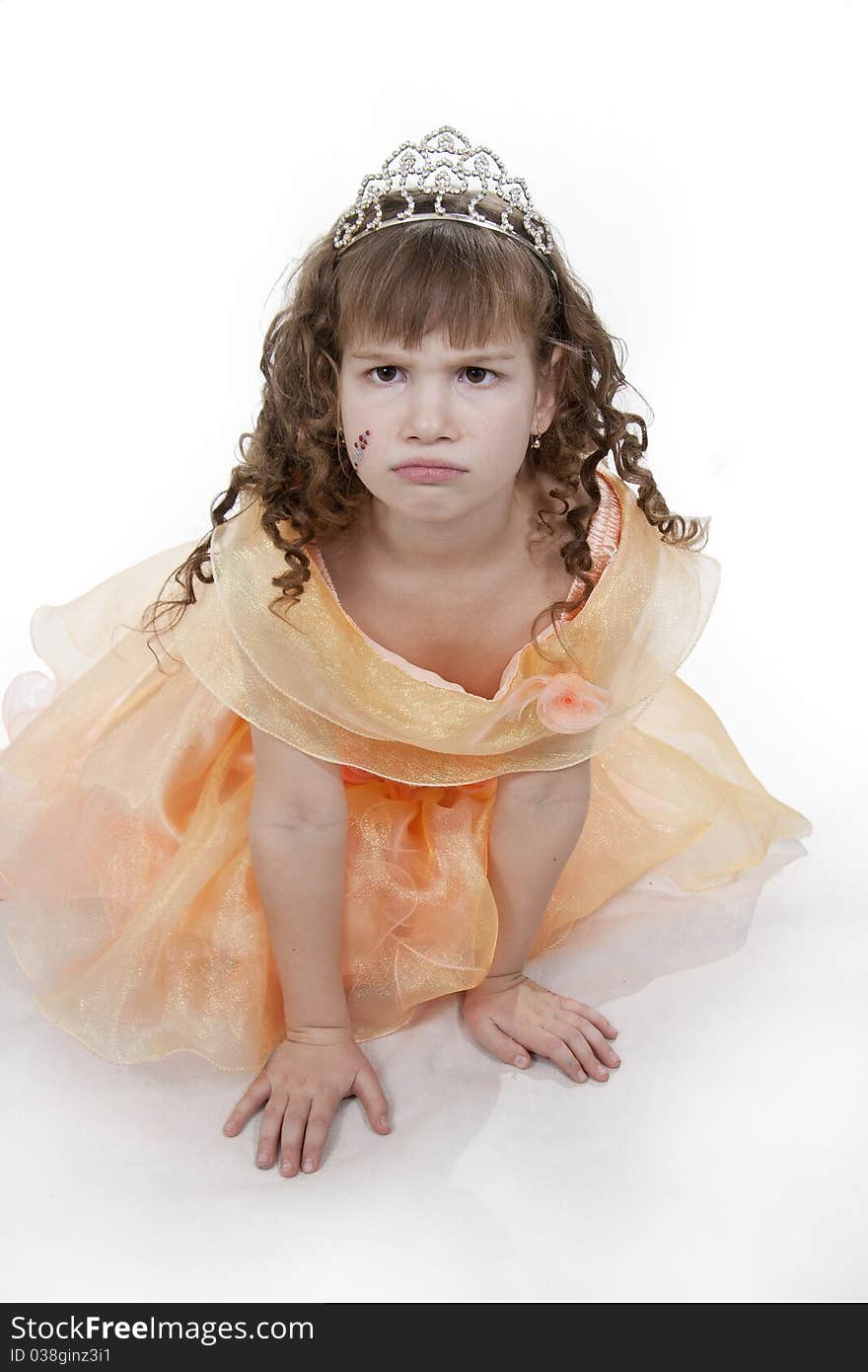 The girl the princess in a orange dress sits opposite to a white background. The girl the princess in a orange dress sits opposite to a white background