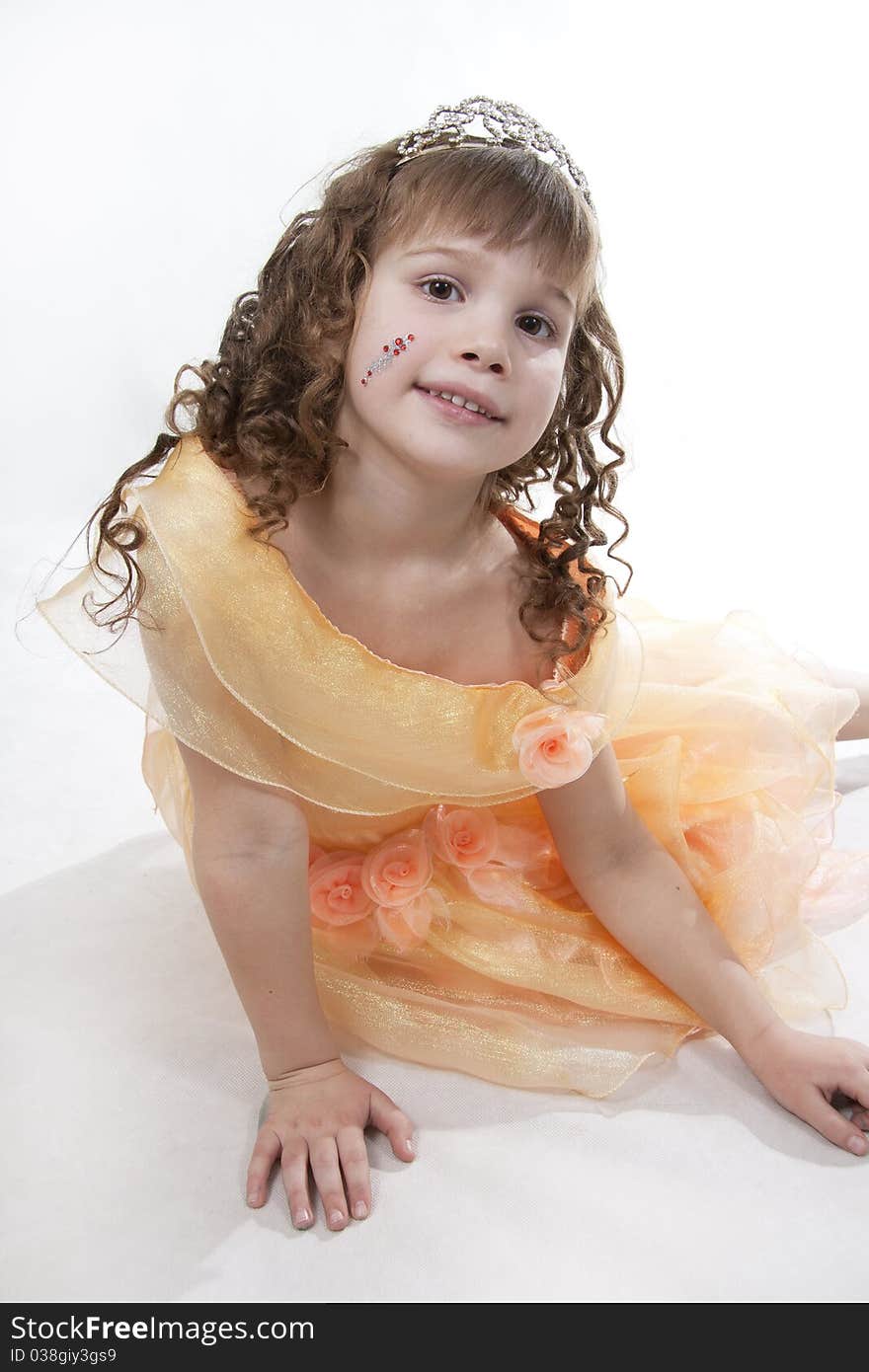 The girl the princess in a orange dress sits opposite to a white background. The girl the princess in a orange dress sits opposite to a white background