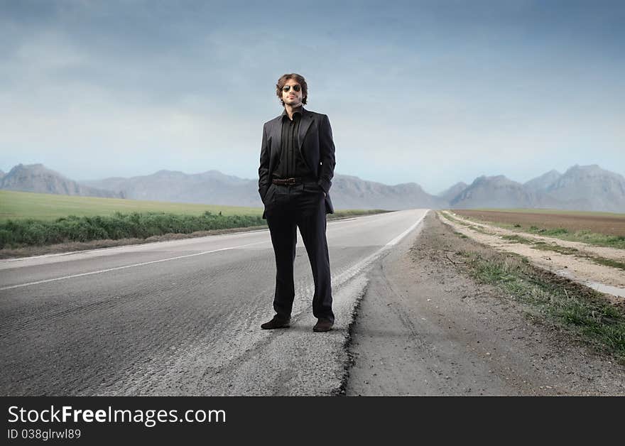 Young elegant man standing on a countryside road. Young elegant man standing on a countryside road