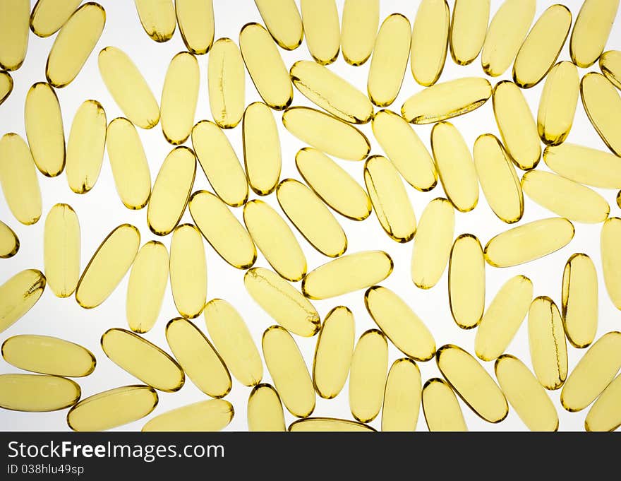 Gold pills or capsules backlit on white for medical or science use. Gold pills or capsules backlit on white for medical or science use