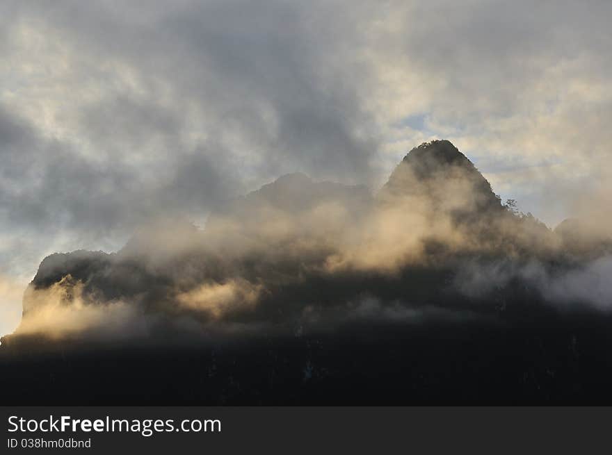 Silhouette of limestone mountain cover with mist in morning.