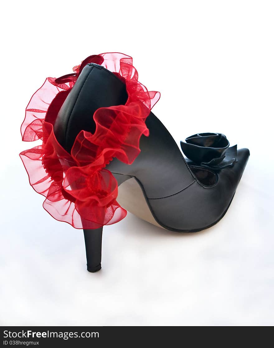 One black shoe with red garter on white background. One black shoe with red garter on white background