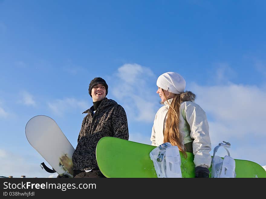 Young smiling couple with snowboards at winter day