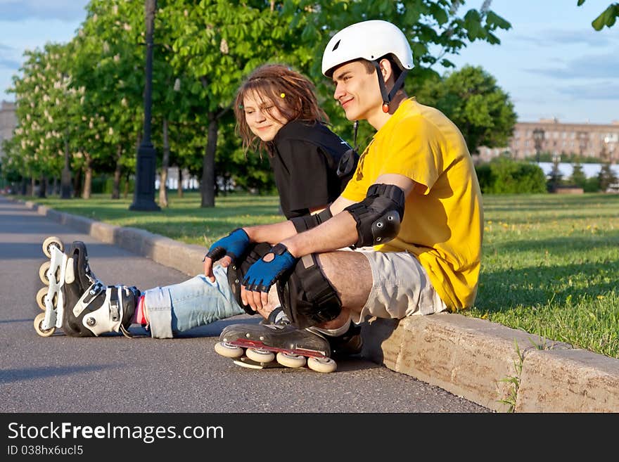 Young heterosexual couple put on inline skates. Young heterosexual couple put on inline skates