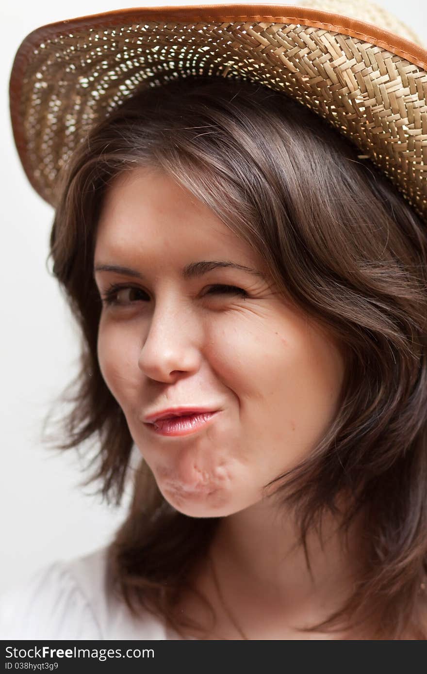 Winking young woman in straw hat on white background