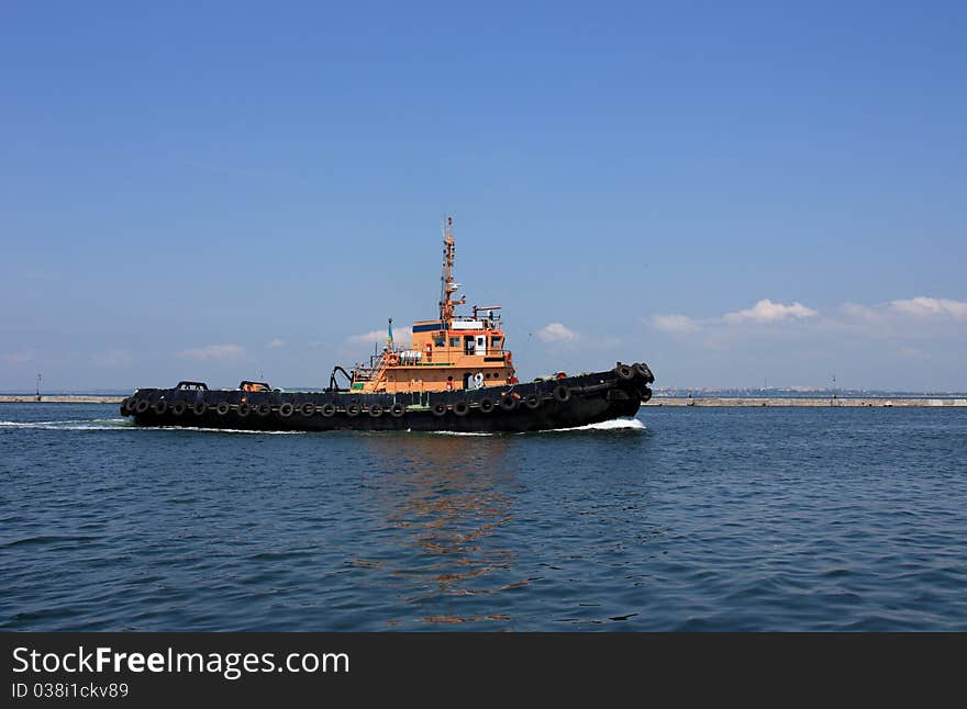 Tugboat underway at speed preparing to guide cruise ship into harbor. Tugboat underway at speed preparing to guide cruise ship into harbor.