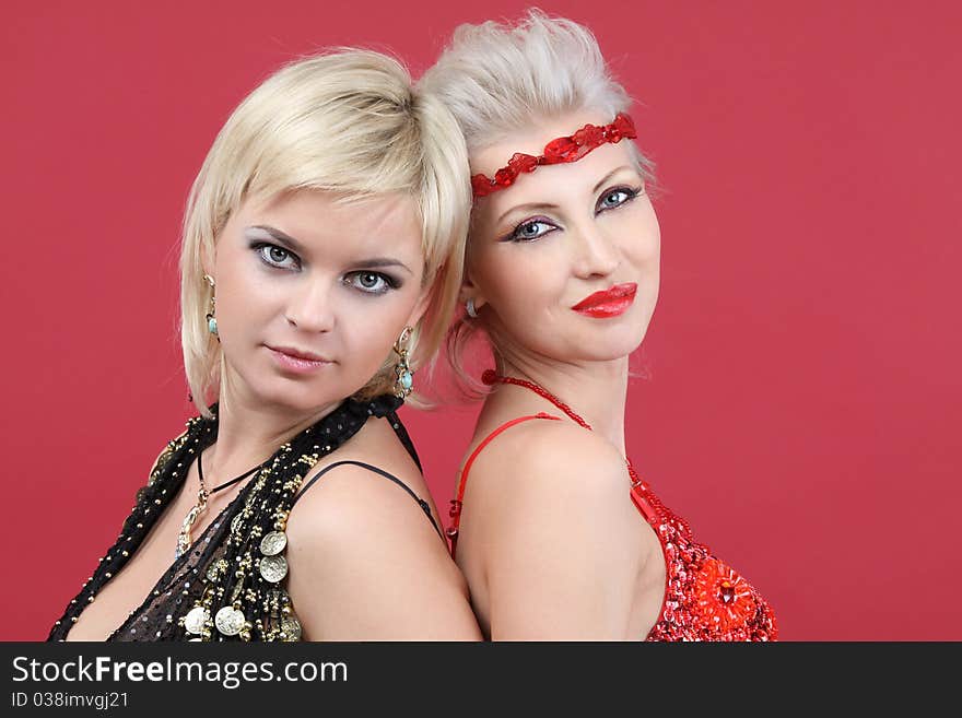 Two young beautiful woman on red background