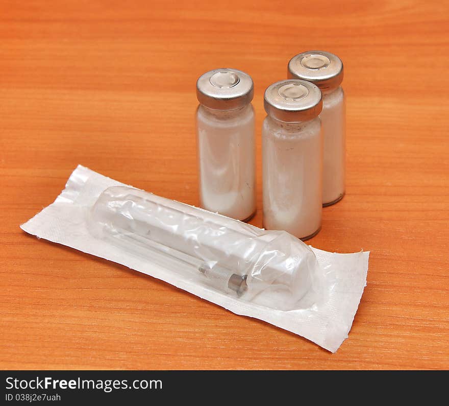 Medicine vials and syringe on wood background