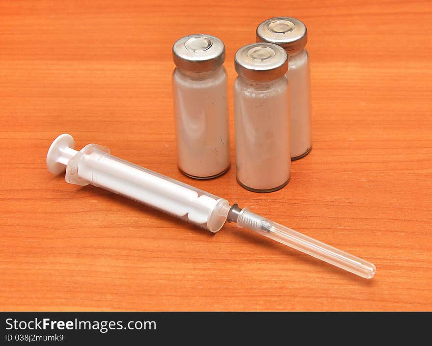 Medicine vials and syringe on wood background