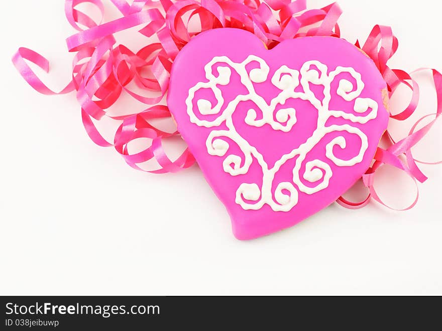 A delicious pink decorated Valentines cookie with ribbons and white background. A delicious pink decorated Valentines cookie with ribbons and white background