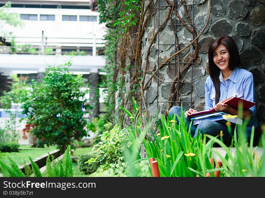 A female student is studying with her laptop in university's park. A female student is studying with her laptop in university's park