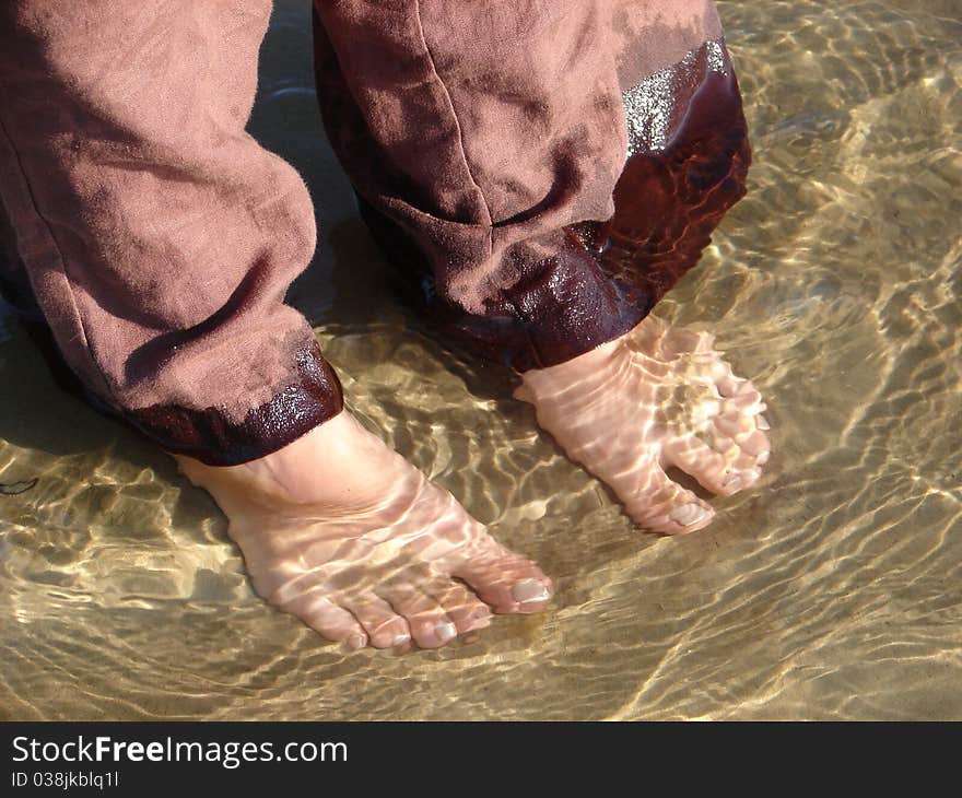 Barefoot woman standing in shallow water in seaside. Barefoot woman standing in shallow water in seaside.