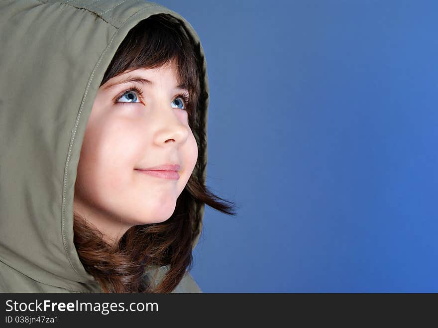 Smiling little child looking up at copyspace isolated on blue background