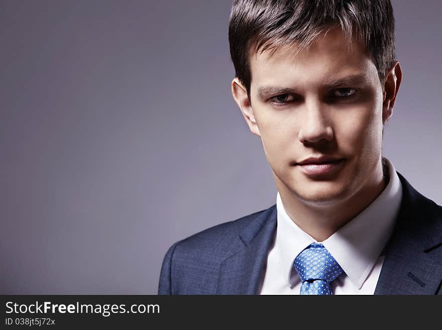 Young businessman in a business suit with a gray background. Young businessman in a business suit with a gray background