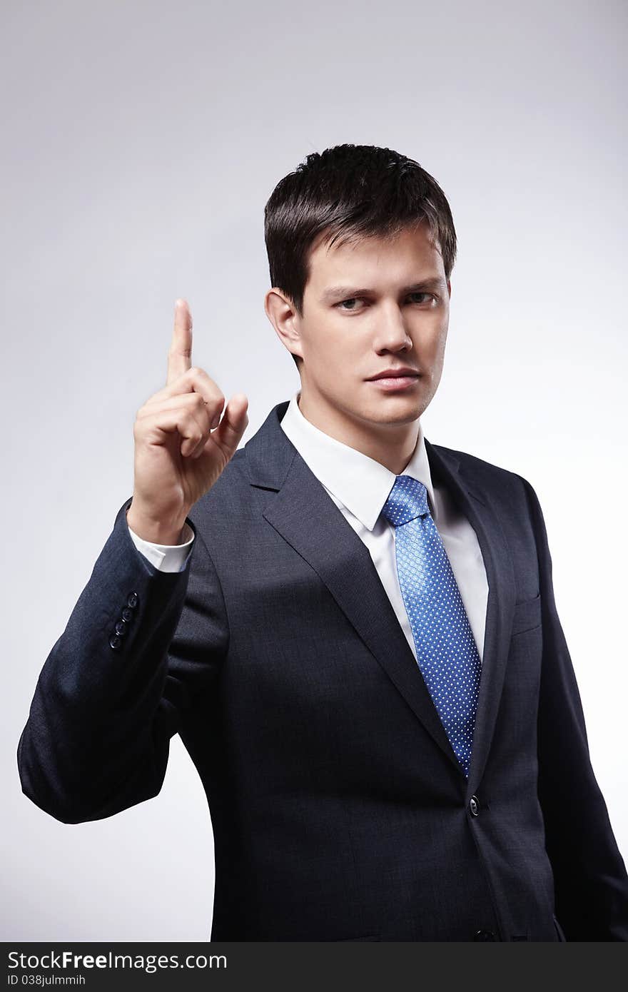 Attractive man in a suit with the index finger up on a gray background. Attractive man in a suit with the index finger up on a gray background