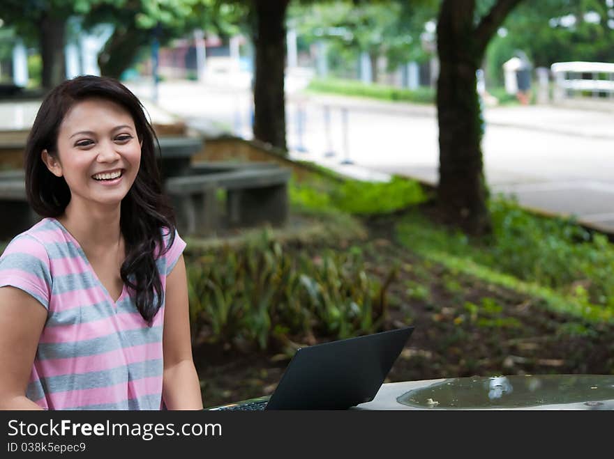 A female student is studying in university's park. A female student is studying in university's park