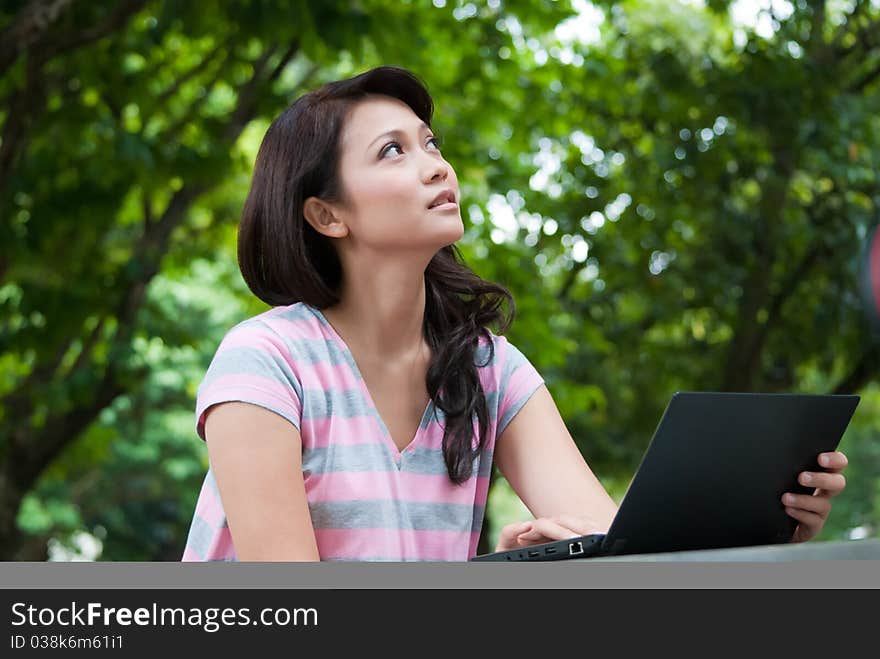 A female student is studying in university's park. A female student is studying in university's park