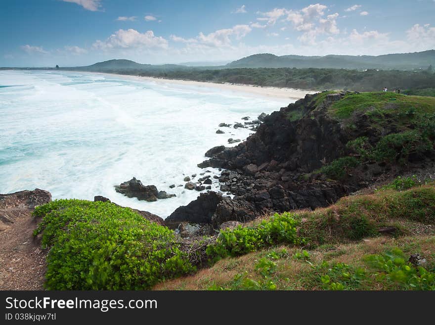 Australian seascape during the day with green hill in foreground (Cabarita Beach,NSW)