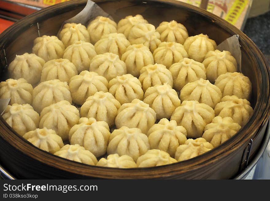 A large bamboo steamer filled with small pork buns (manju) shaped like little flowers. Japanese food. A large bamboo steamer filled with small pork buns (manju) shaped like little flowers. Japanese food.