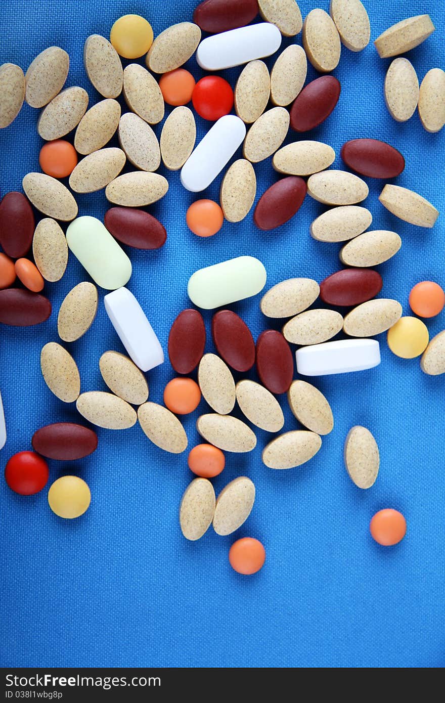 A group of various pills sit on a blue background. A group of various pills sit on a blue background.